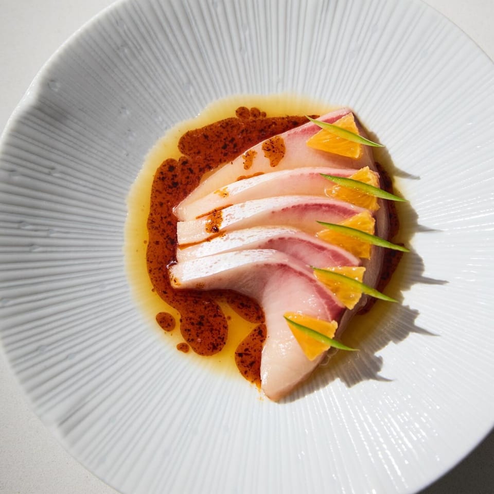 Edgemar Restaurant's New American Hamachi Crudo, garnished with orange segments and green herbs.