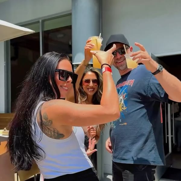 Three smiling people in sunglasses, two holding drinks, enjoying themselves at Edgemar Restaurant + Lounge.