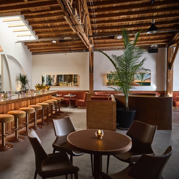 Edgemar Restaurant + Lounge interior with a long bar, velvet stools, and cozy seating areas.