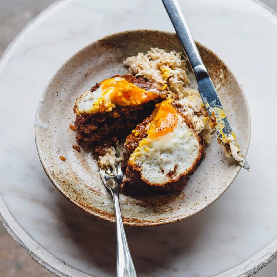 New-American dish with two fried eggs on top of a meat patty, served with rice.