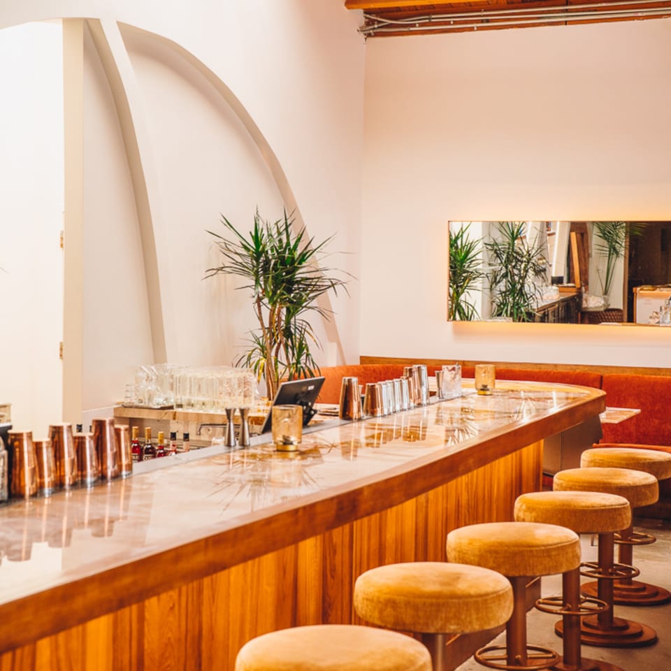 Edgemar Restaurant + Lounge bar with wooden counter, gold stools, and red booth seating.